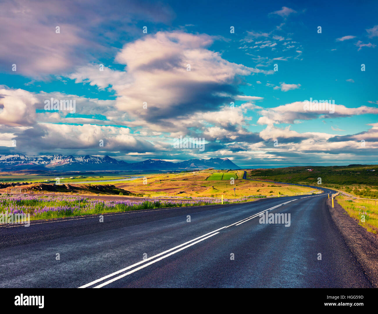 Leere Asphaltstraße mit bunten bewölkten Himmel. Schöne Outdoor-Landschaft in Island, Europa. Stockfoto