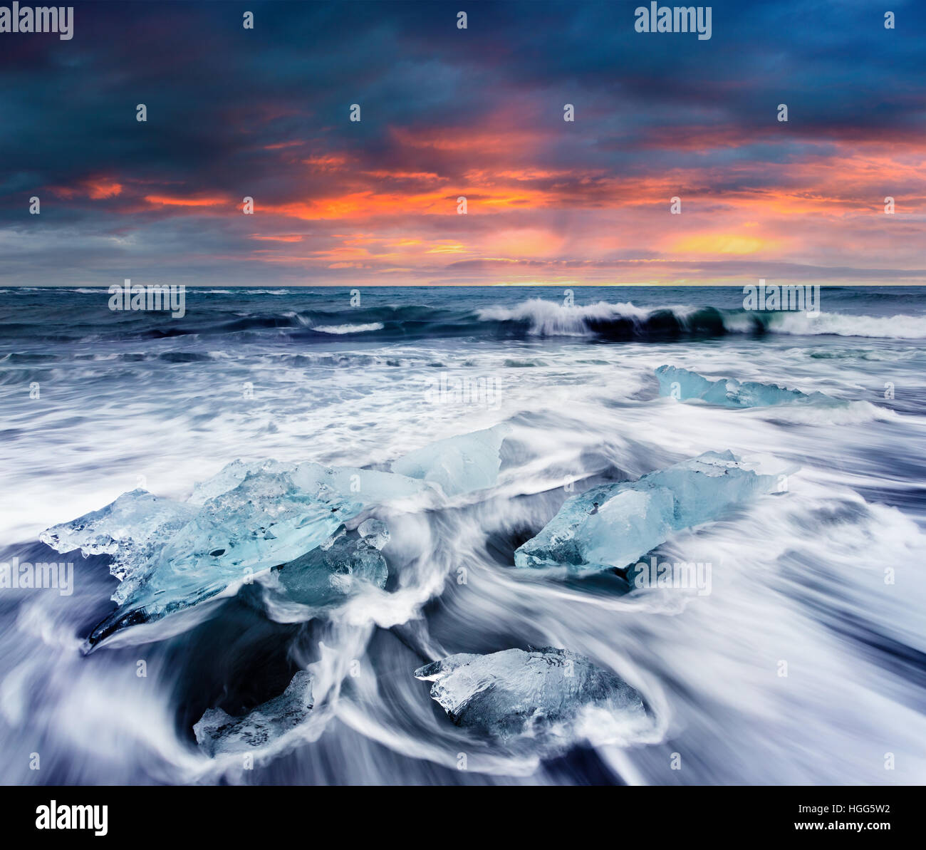 Umspült von den Wellen am Strand von Jökulsárlón Eisblöcke. Dramatische Sommer Sonnenaufgang im Vatnajökull-Nationalpark, Südost-Island. Stockfoto