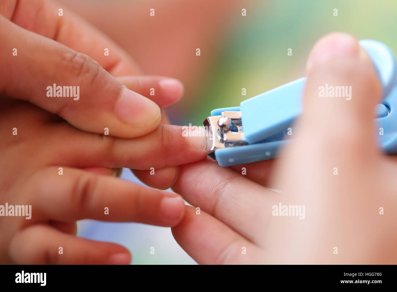 Blaue Nagelknipser, Fingernägel schneiden eines Kindes durch die Mutter. Stockfoto