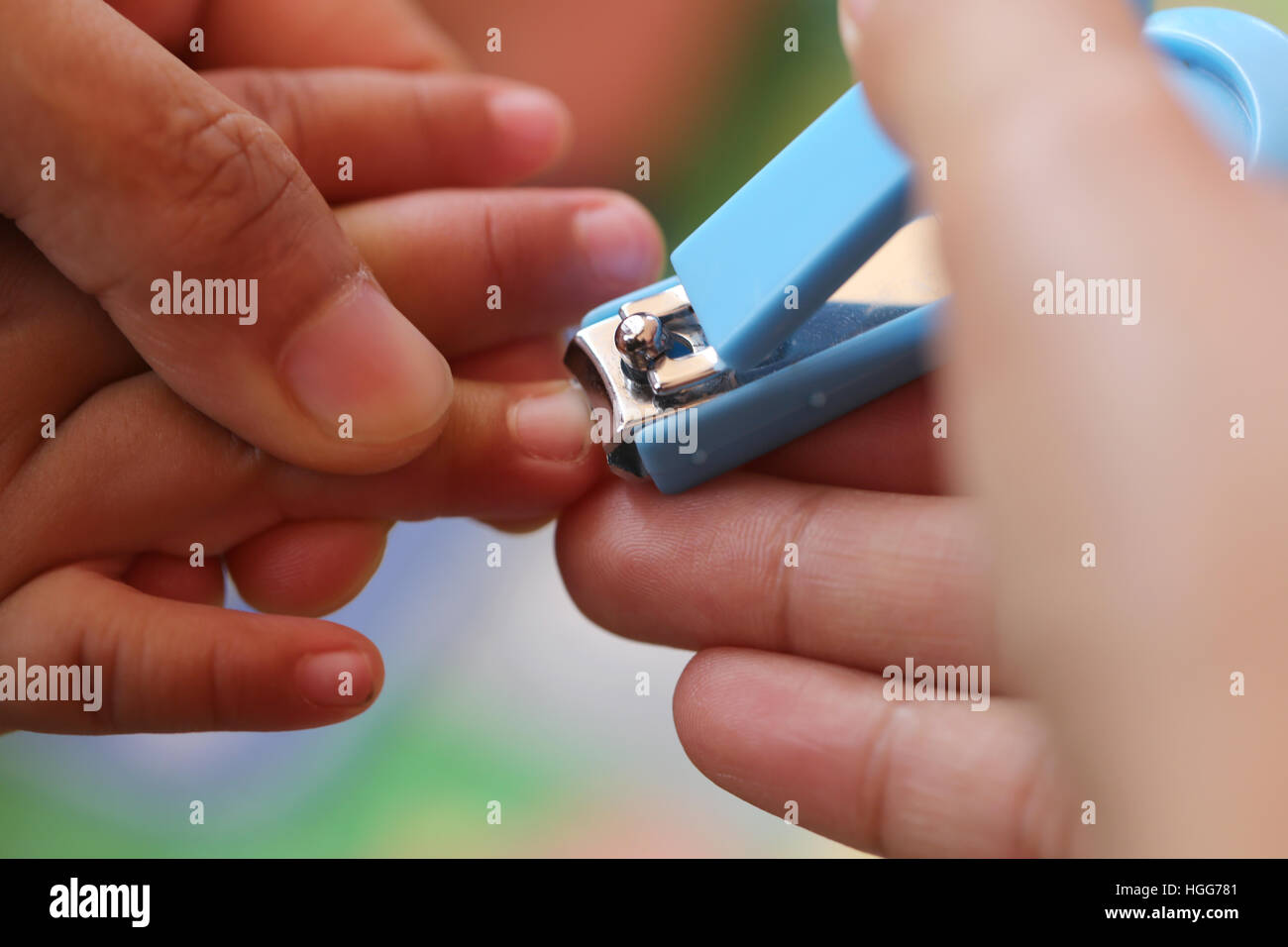 Blaue Nagelknipser, Fingernägel schneiden eines Kindes durch die Mutter. Stockfoto