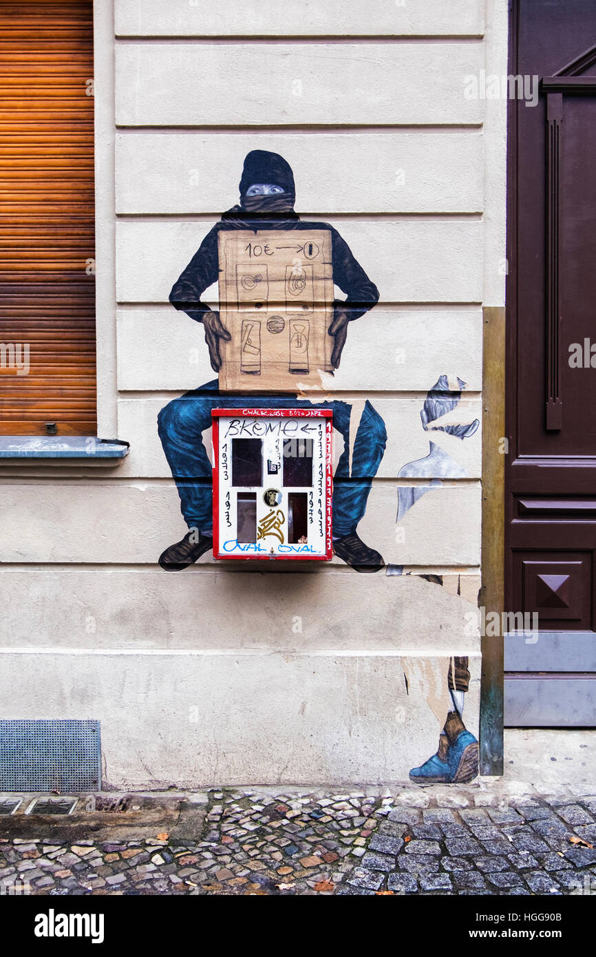 Berlin, Mitte. Street-Art. Maskierter Mann Olding Karton Gumball Maschine Stockfoto