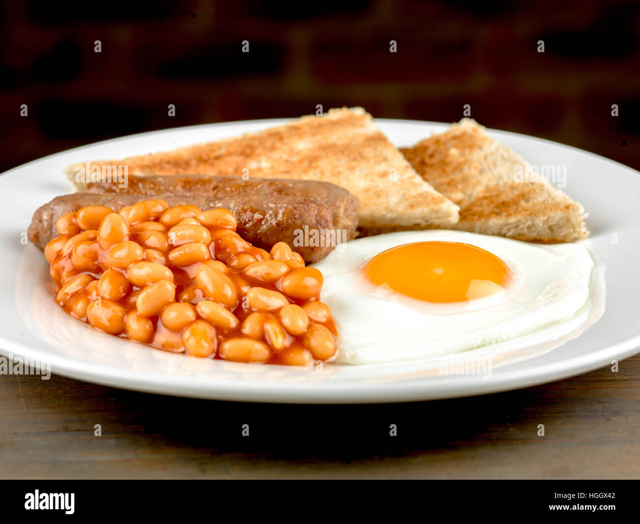 Frisch zubereitete Authentische gebratene Englische Frühstück mit zwei Würstchen Spiegelei und gebackene Bohnen mit Toast als Flach Ohne Menschen Stockfoto