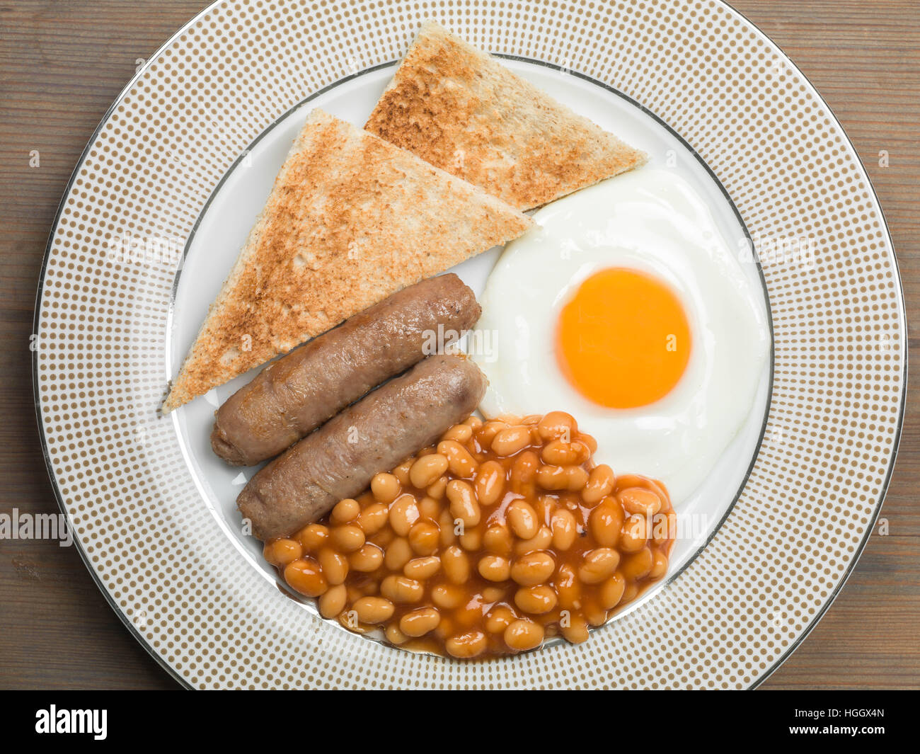 Frisch zubereitete Authentische gebratene Englische Frühstück mit zwei Würstchen Spiegelei und gebackene Bohnen mit Toast als Flach Ohne Menschen Stockfoto