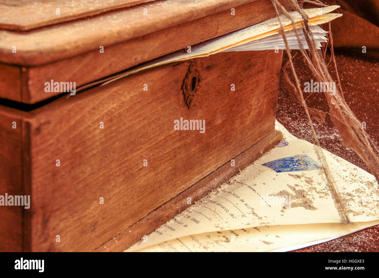 Eine geheimnisvolle Holzkiste mit alten Papieren in Spinnweben und Staub bedeckt Stockfoto