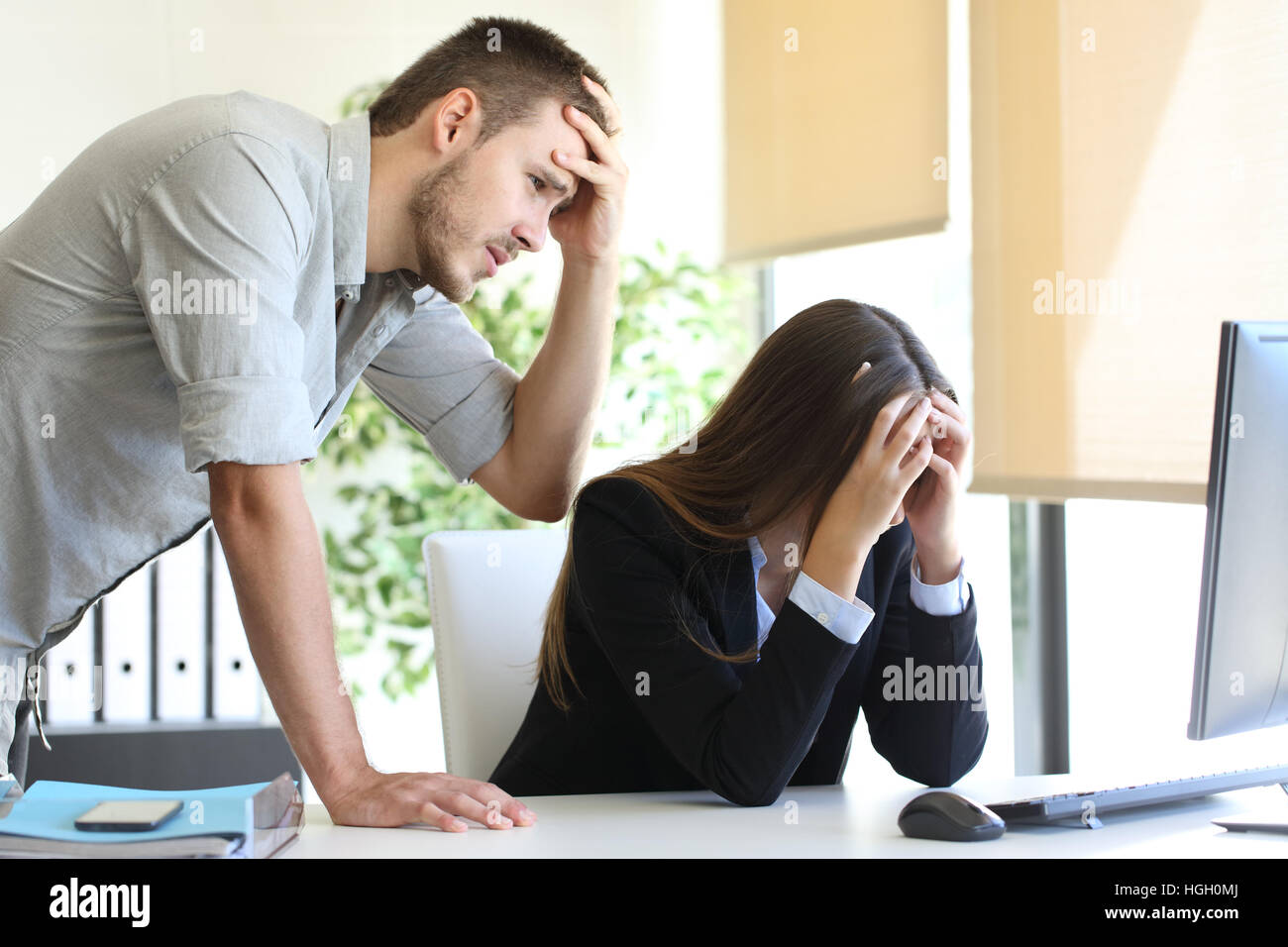 Zwei sorgen Mitarbeiter mit einem Desktopcomputer beklagen nach ein großer Fehler im Büro Stockfoto