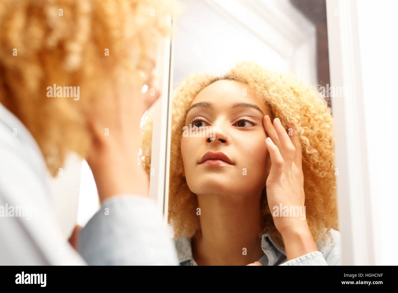 Erste Falten. Die Alterung der Haut. Frau schaut in den Spiegel schauen nach den ersten Anzeichen des Alterns. Stockfoto