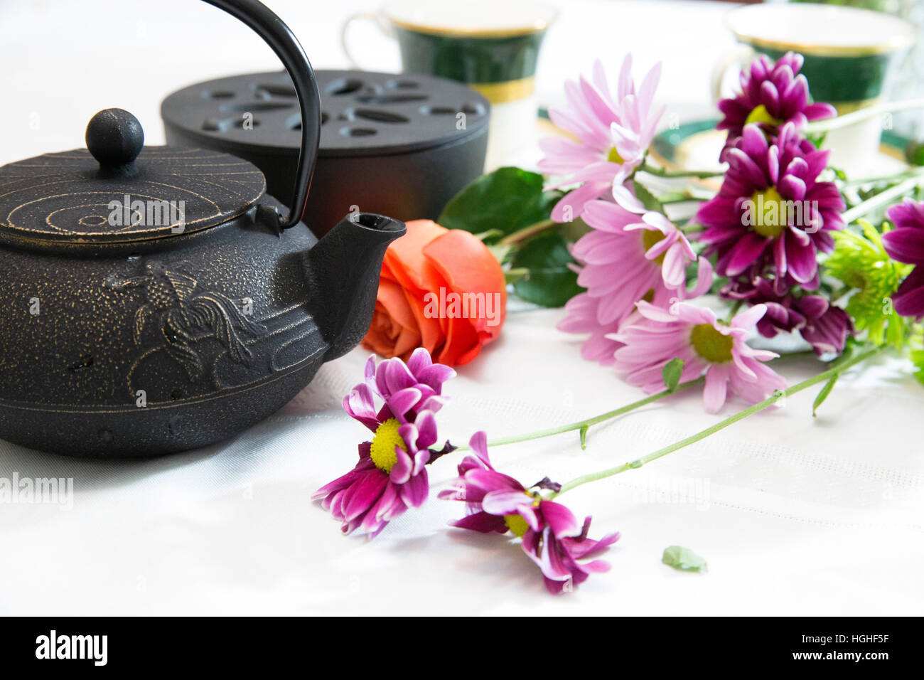 Ein Antik Eisen-Teekanne mit Wildblumen auf einer weißen Tischdecke Stockfoto