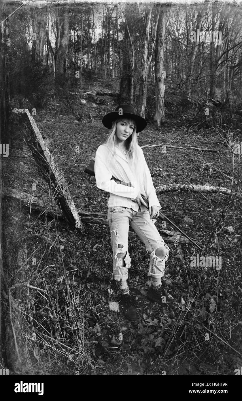 Junge blonde Frau im Wald mit einer Pistole Stockfoto