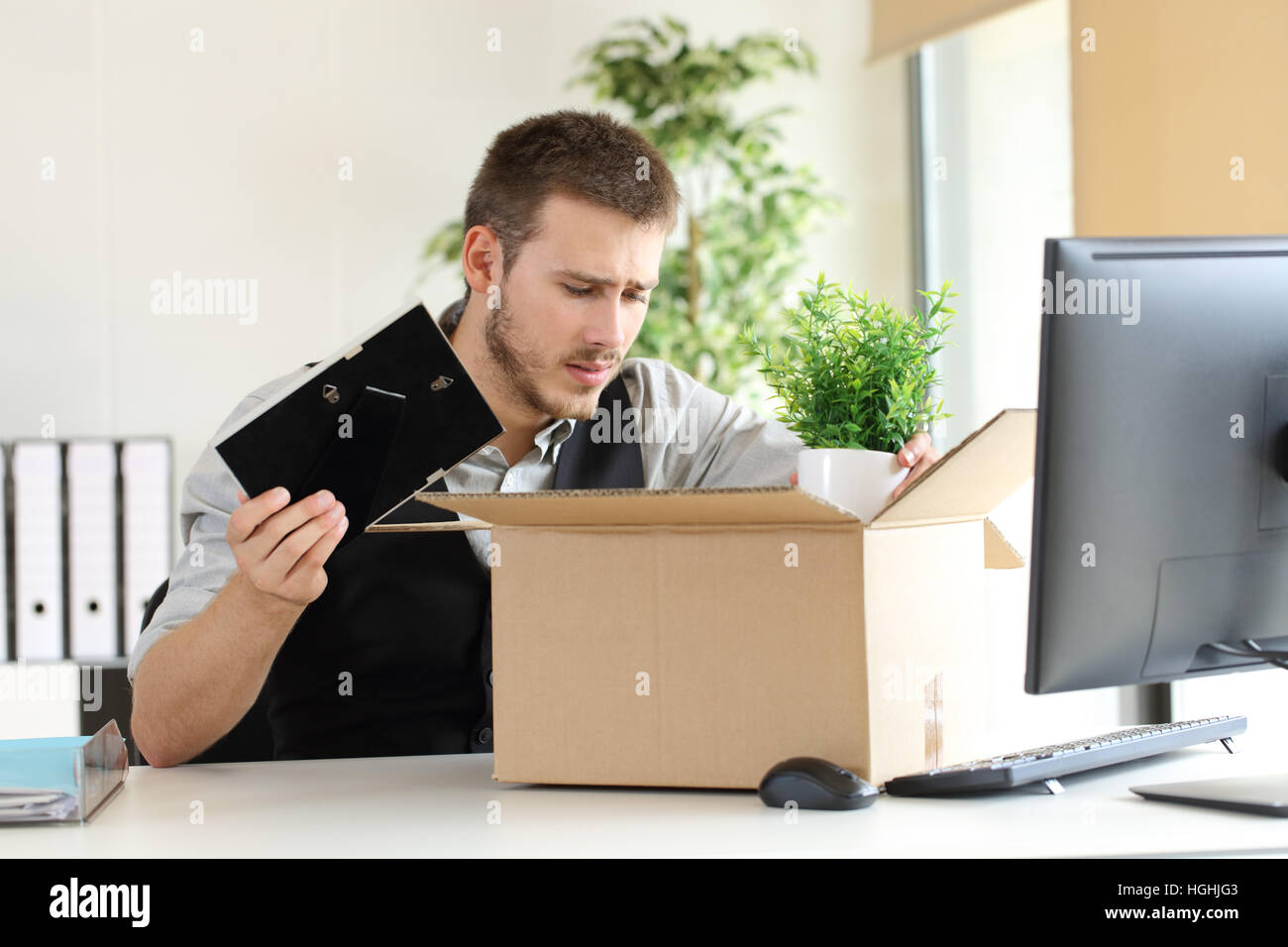 Traurig gebrannten Geschäftsmann setzen seine Habseligkeiten in einem Feld von einem Desktop im Büro Stockfoto