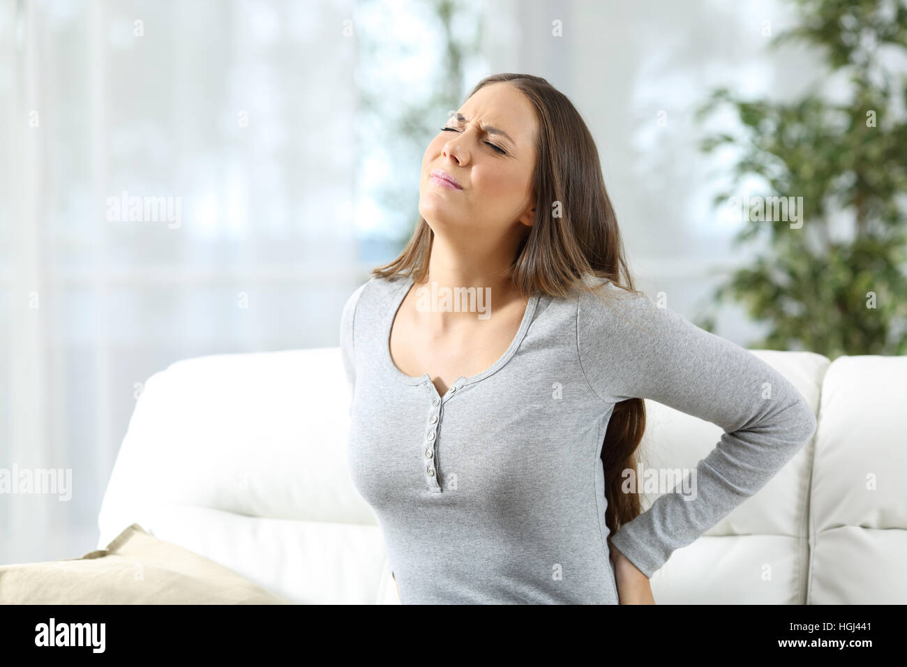 Frau leiden Rückenschmerzen und klagenden sitzen auf einer Couch im Wohnzimmer zu Hause Stockfoto