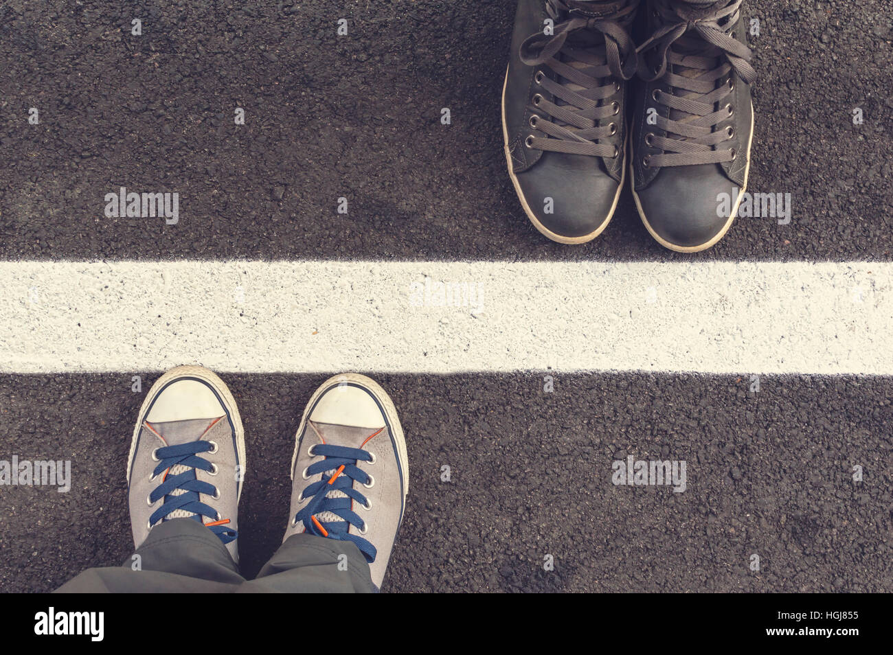 Zwei Paar Turnschuhe auf einer Asphapt Straße. Oben in der Ansicht. Stockfoto