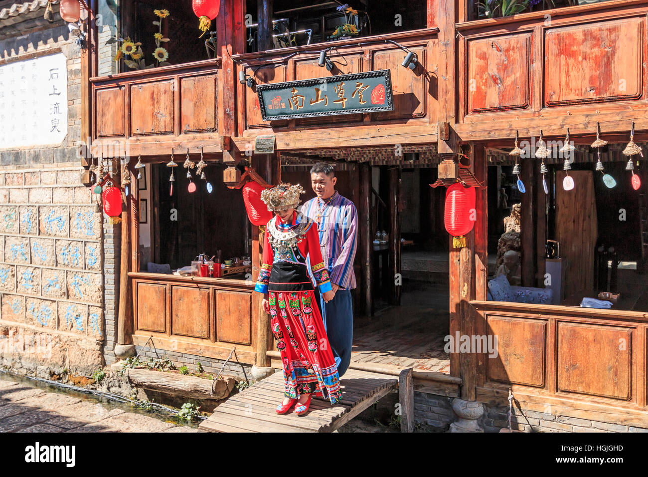 Lijiang, China - 14. November 2016: Junge chinesische paar gekleidet mit Trachtenmode halten Sie die Hände vor einem alten Gebäude im Sh Stockfoto