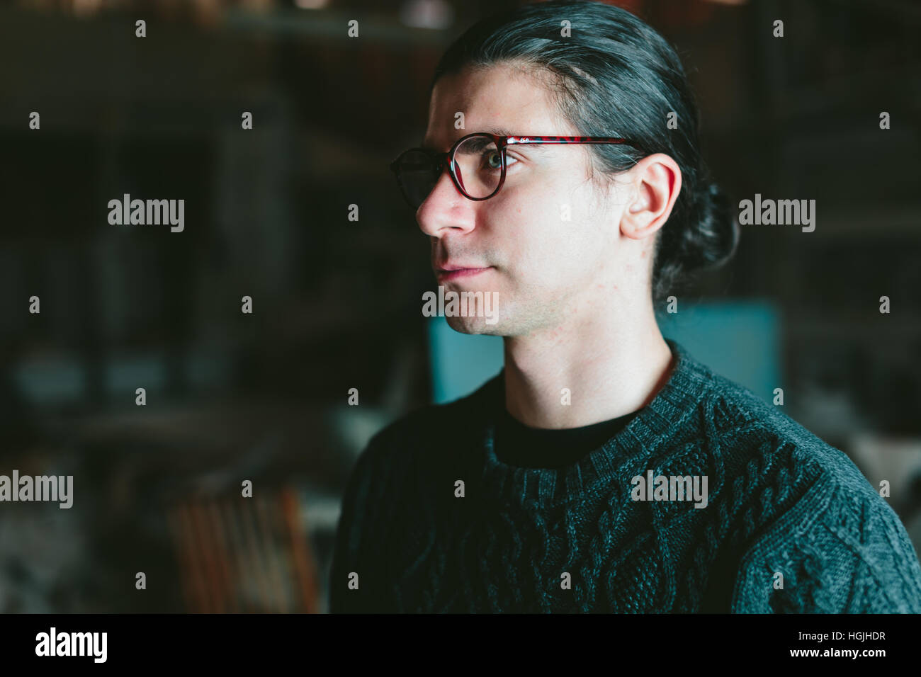 junger hübscher Mann mit Brille auf einem dunklen Hintergrund Stockfoto