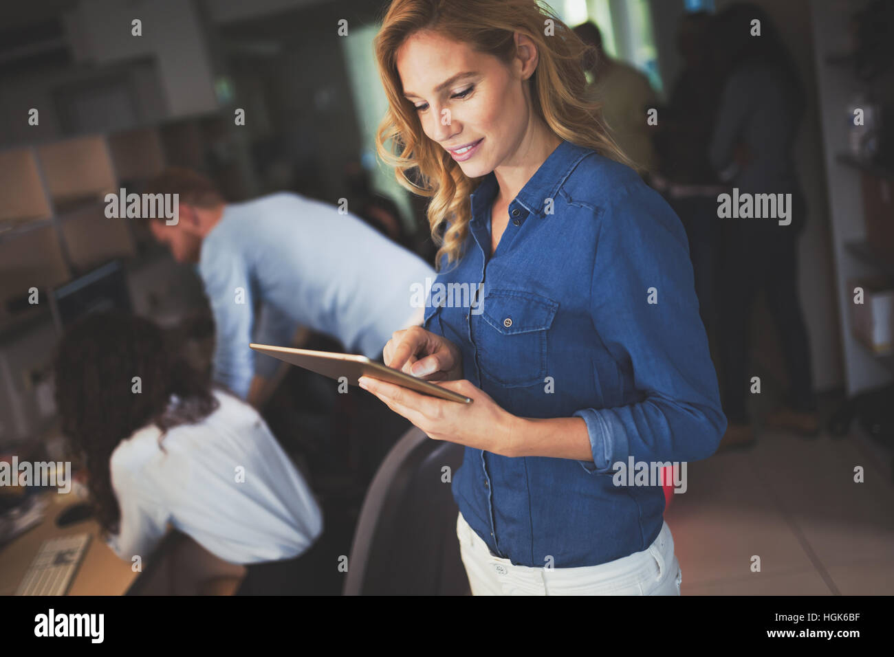 Schöne blonde Geschäftsfrau Holding Tablet im modernen Büro Stockfoto
