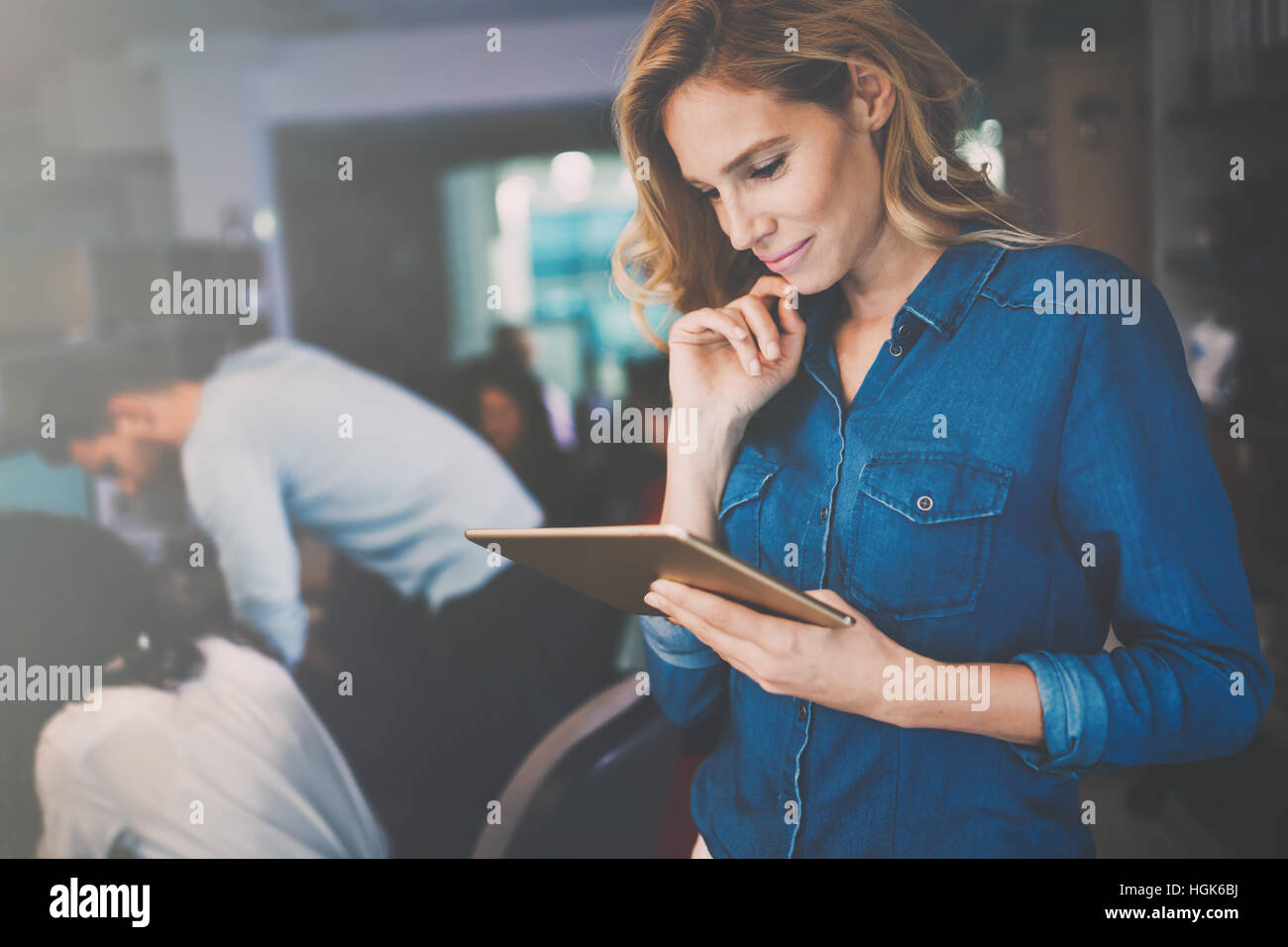Schöne blonde Geschäftsfrau Holding Tablet im modernen Büro Stockfoto