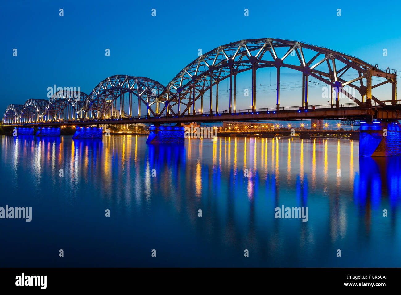 Beleuchtete Eisenbahnbrücke in der Dämmerung in Riga, Lettland Stockfoto