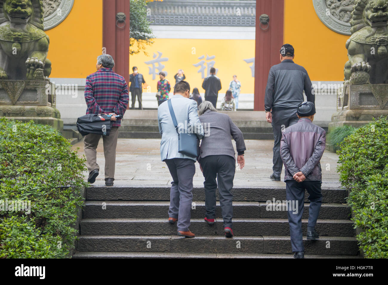 Menschen helfen, seine alte Mutter Treppe in einem Tempel in Shanghai, China Stockfoto