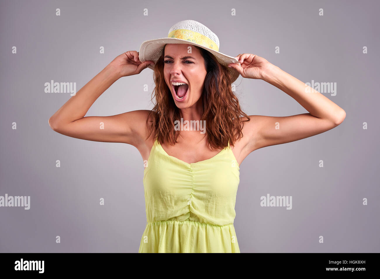 Eine schöne junge Frau schreiend in einem grünen Kleid und Hut Stockfoto