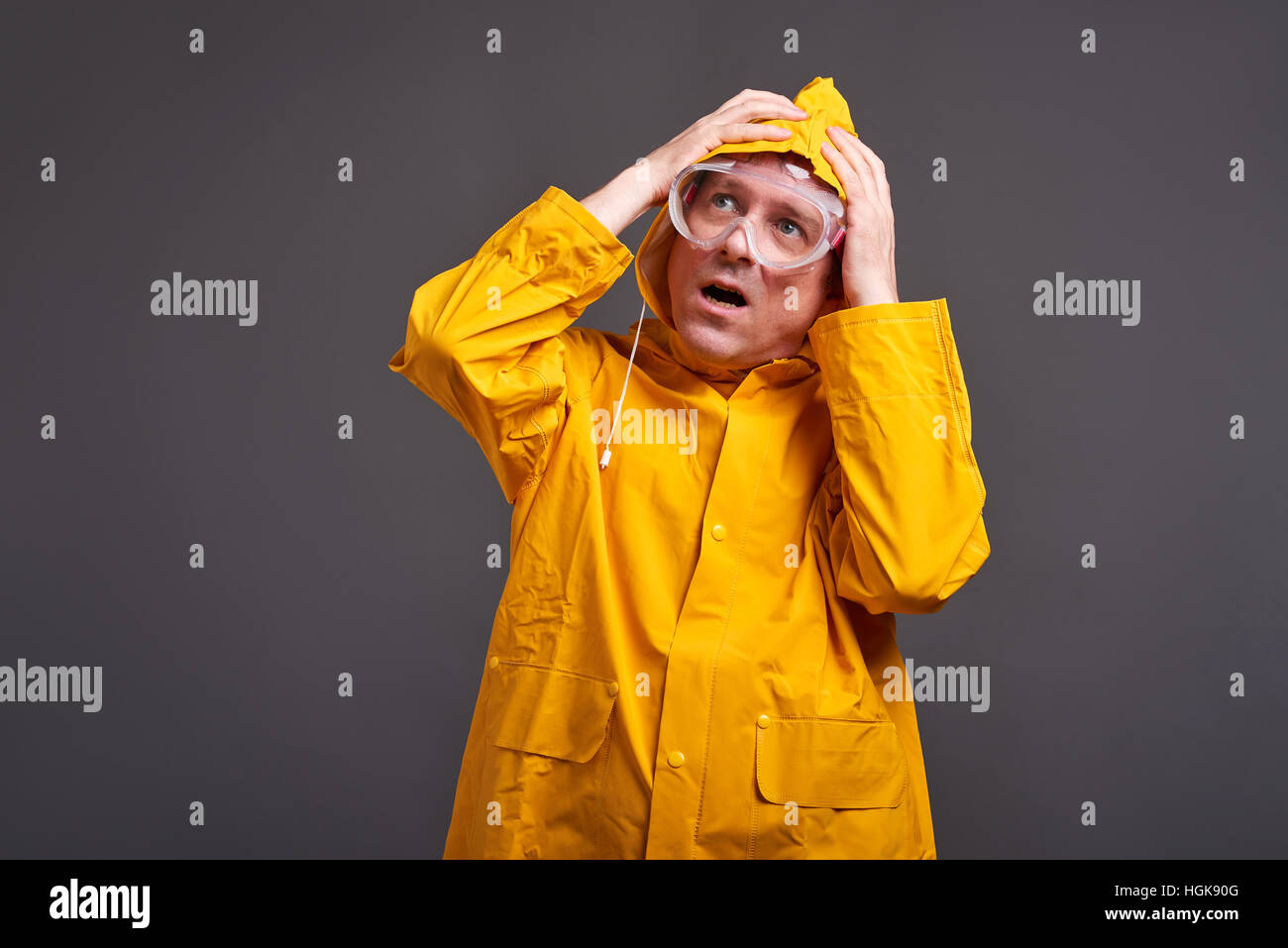 Ein Mann mittleren Alters in einem gelben Regenmantel und Schutzbrille Gefühl Angst Stockfoto