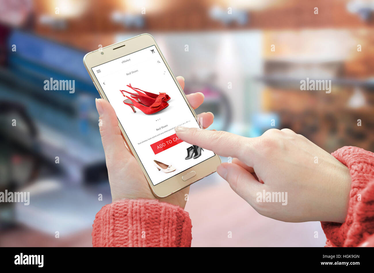 Shopping Website-app auf dem Smartphone. Frau, mit mobilen Gerät und kaufen rote Schuhe. City Shopping centre im Hintergrund. Stockfoto