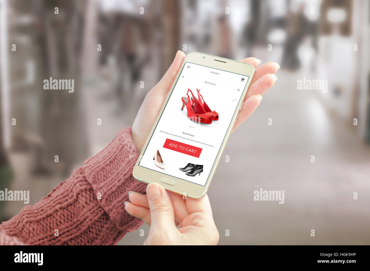 Frau mit Smartphone mit Commerce-Website. Freundliches app Benutzeroberfläche mit Frau Schuhe. Einkaufszentrum im Hintergrund. Stockfoto