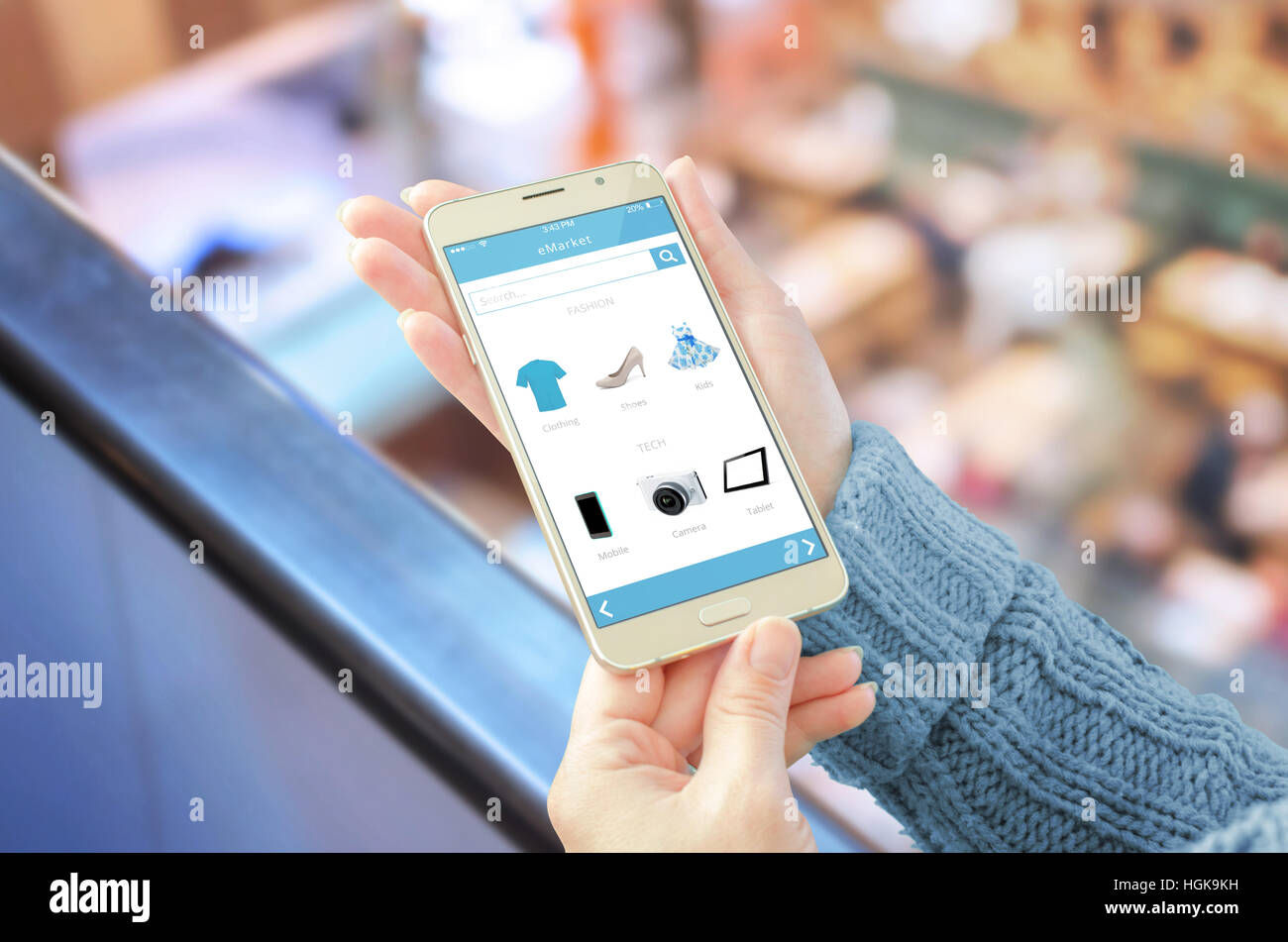 Frau zeigt Online-shop app auf dem Handy. Einkaufszentrum im Hintergrund. Stockfoto
