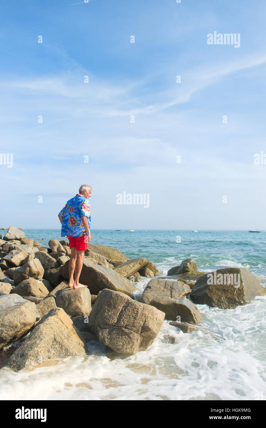 Senior-Mann mit Blick auf das Meer trägt ein blaues Hawaii-Hemd Stockfoto