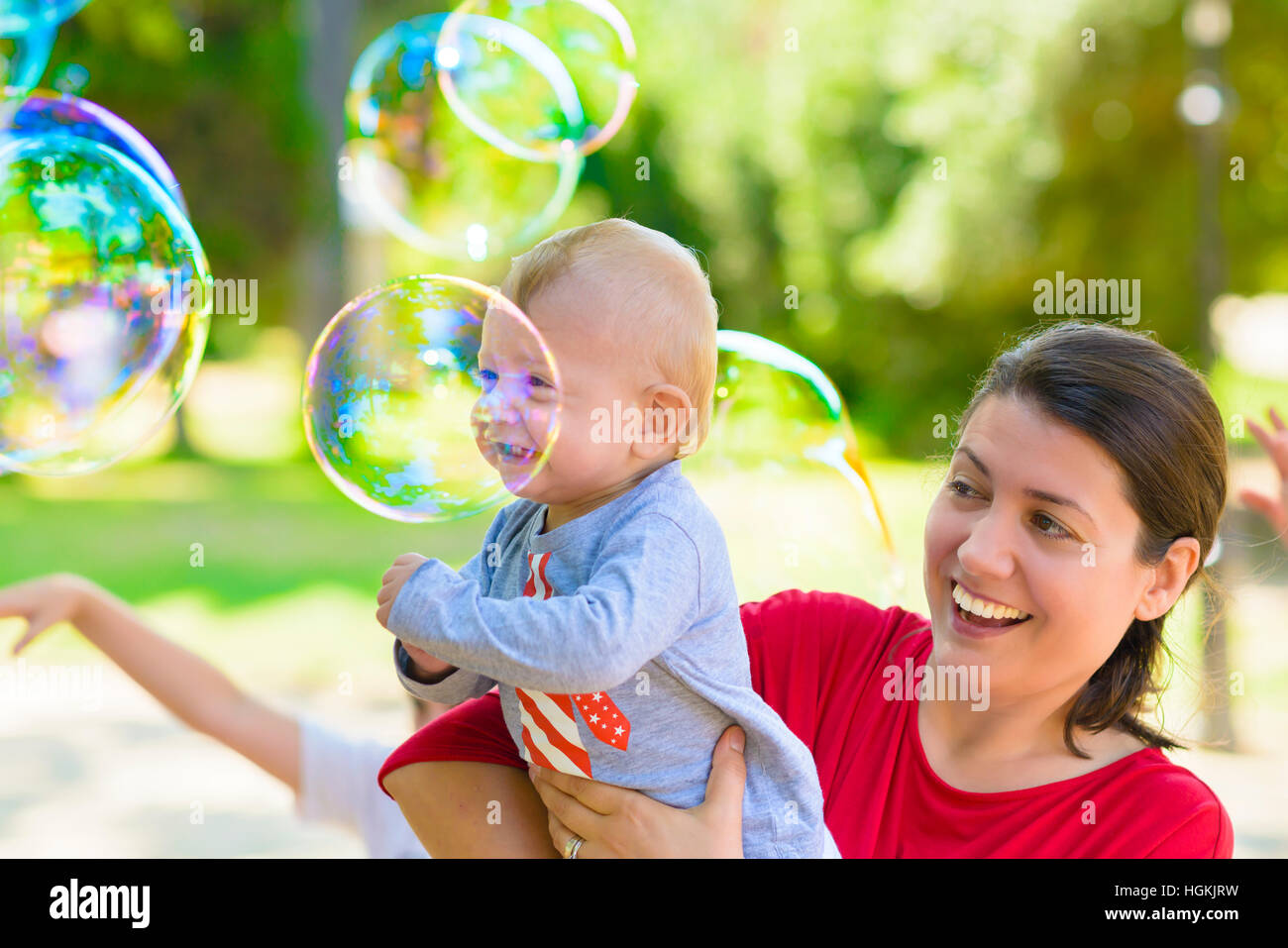 Cute Baby und seine Mutter fangen Seifenblasen in einem Sommertag Stockfoto