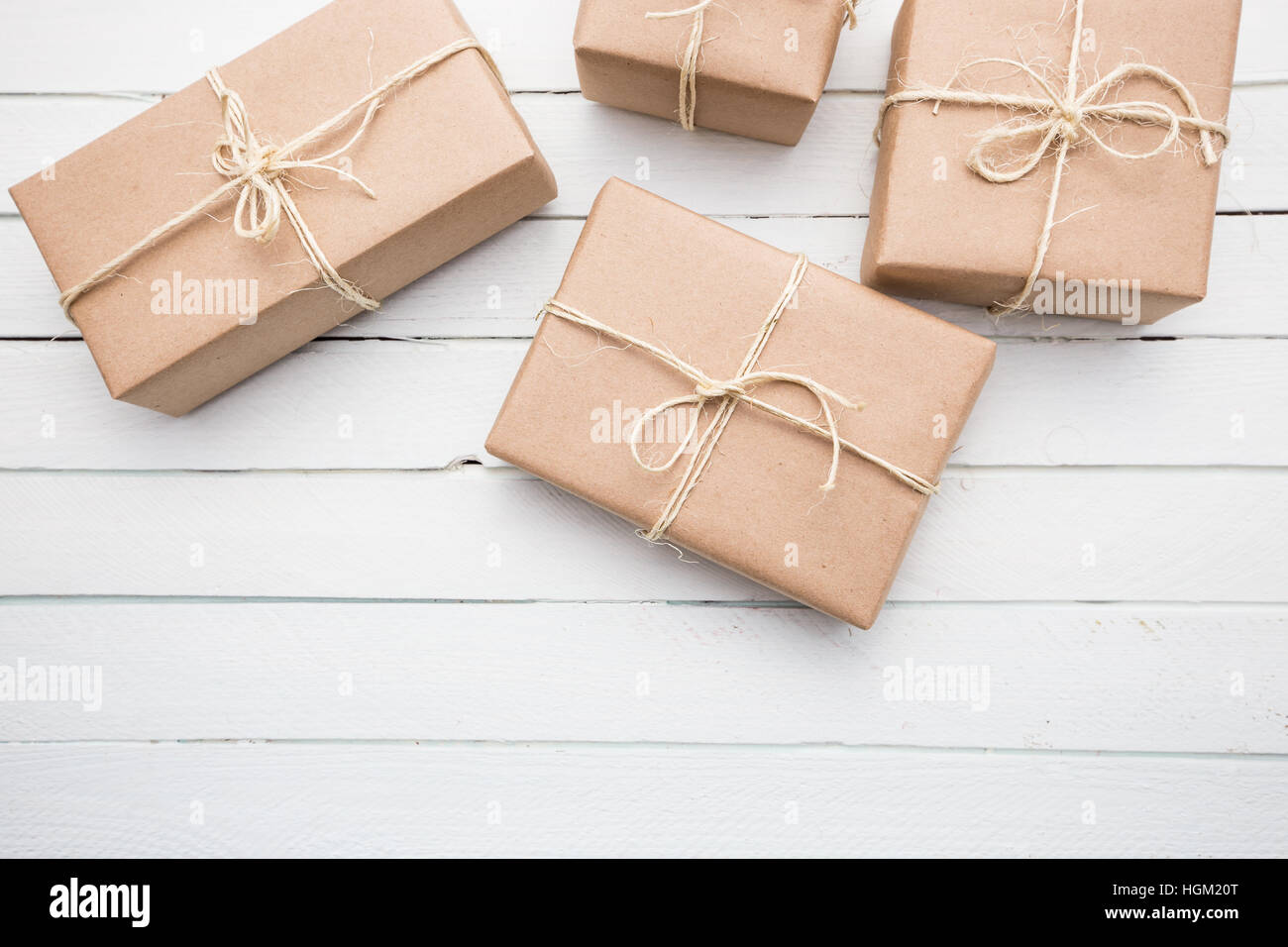 Weihnachtspaket Stil rustikal braun Papier gefesselt mit Streichern. Weiße Holz Hintergrund. Stockfoto