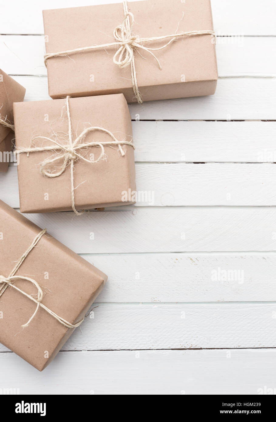 Weihnachtspaket Stil rustikal braun Papier gefesselt mit Streichern. Weiße Holz Hintergrund. Stockfoto