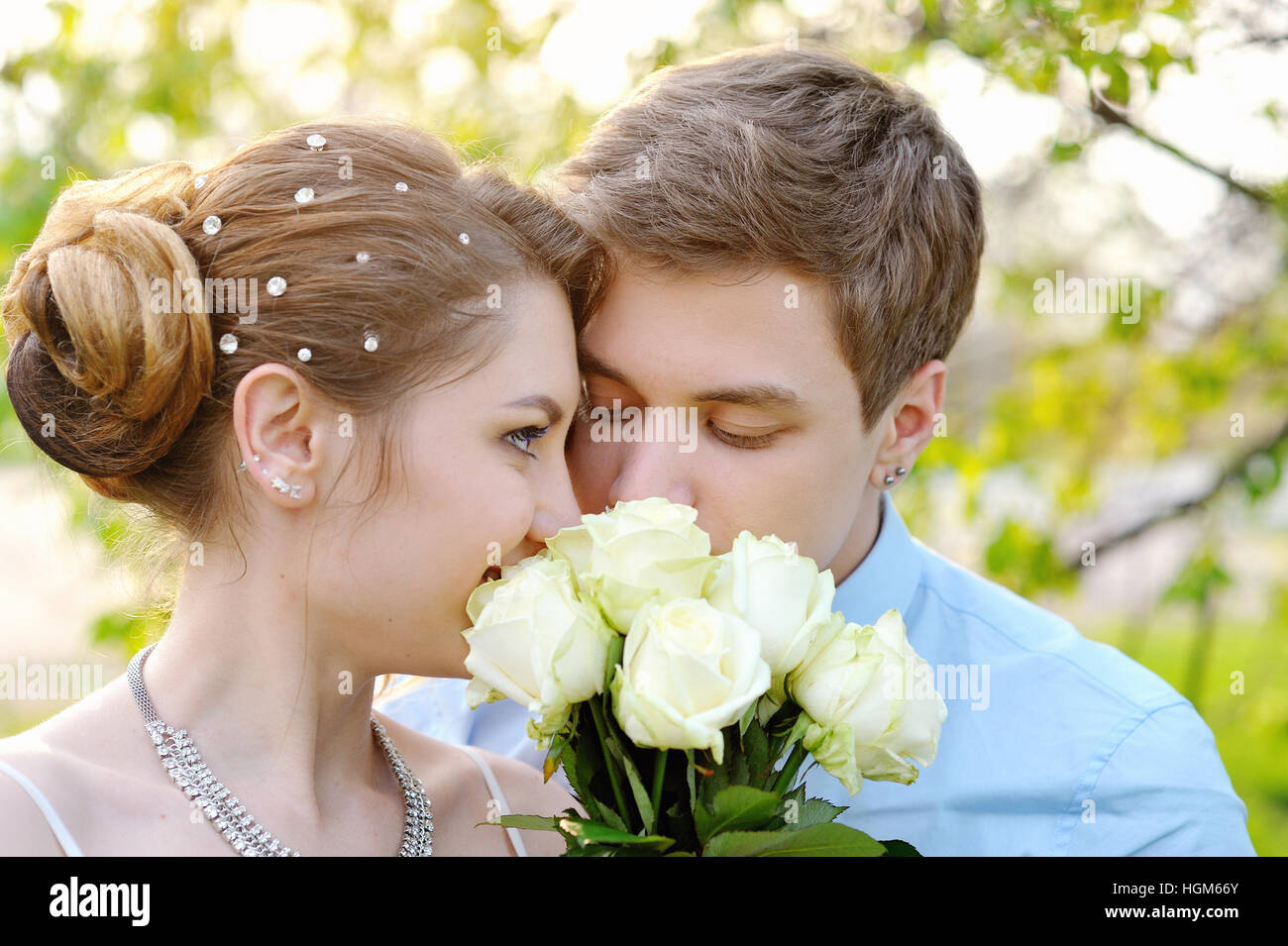 Braut und Bräutigam im Frühlingspark riechen eine weiße rose Stockfoto