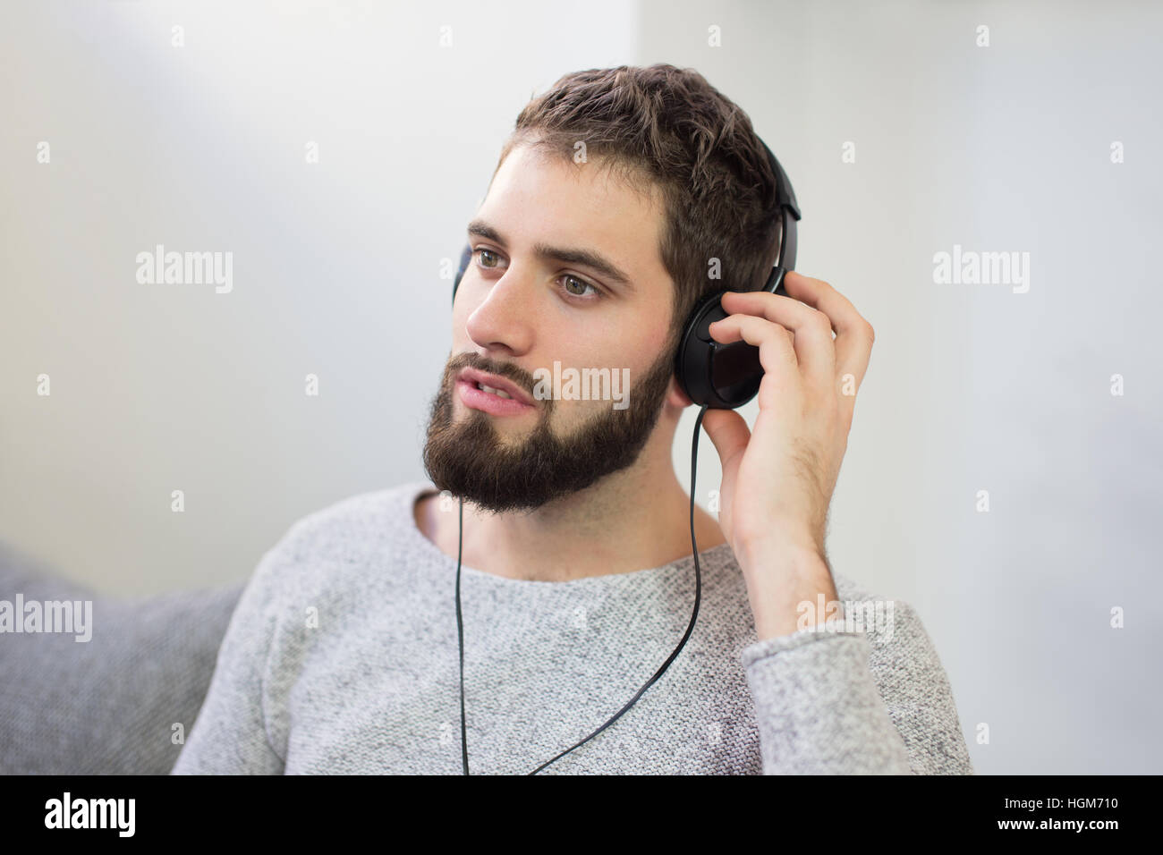 Junger Mann hören Entspannungsmusik indoor, auf sofa Stockfoto
