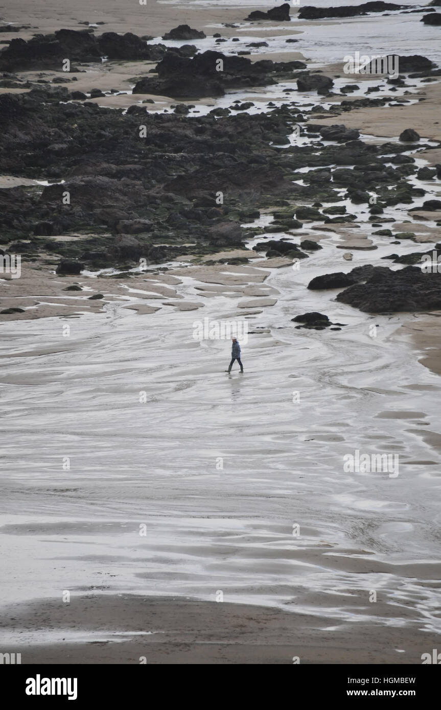 Ein einsamer Wanderer an einem Strand in Cornwall im Winter. Stockfoto
