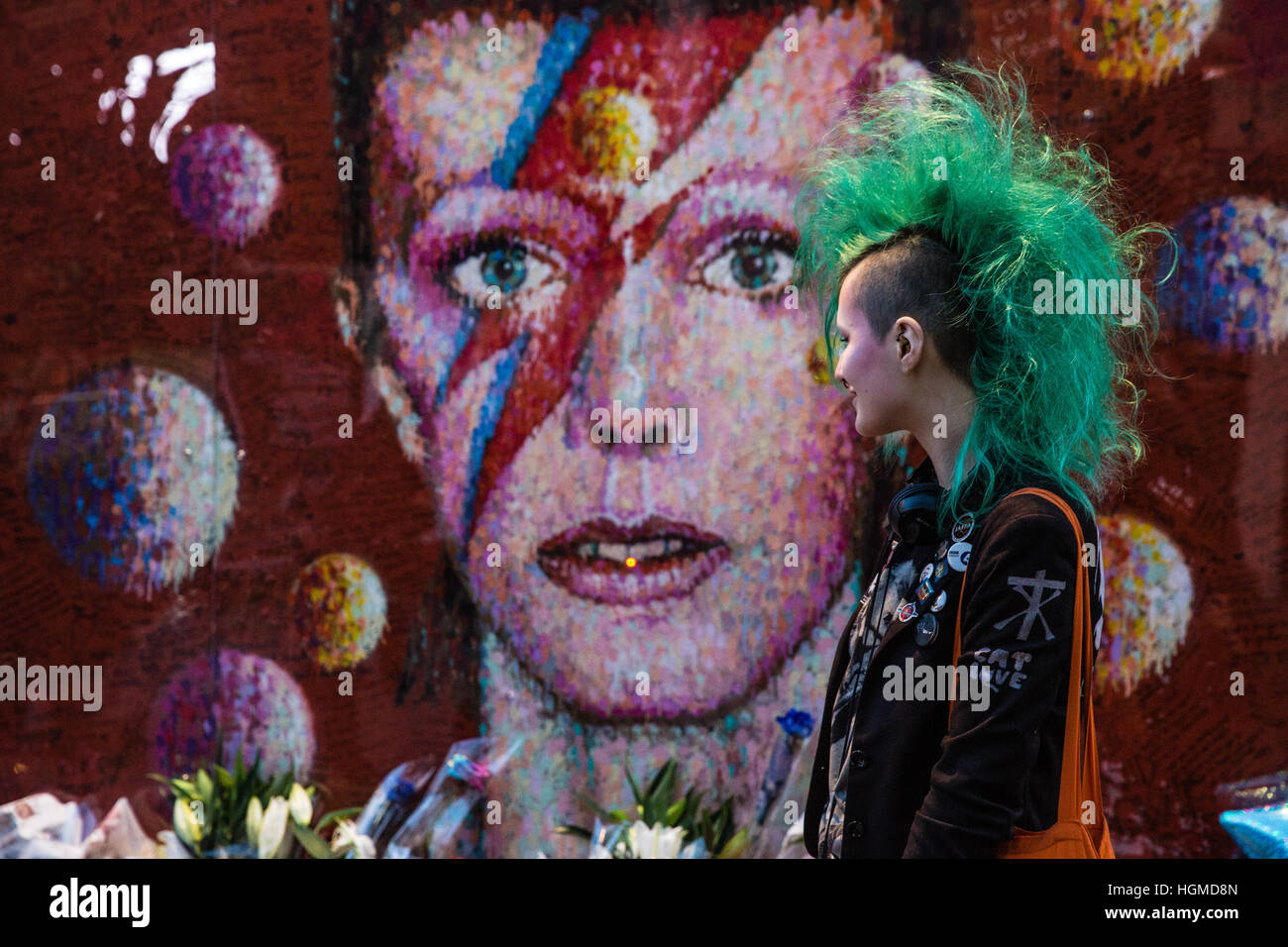 London, UK. 10. Januar 2017.  Eine Mädchen mit einem grünen Mohikaner Haarschnitt ist eine Hommage an David Bowie vor einem Wandgemälde in Brixton am ersten Jahrestag seines Todes. Bildnachweis: Mark Kerrison/Alamy Live-Nachrichten Stockfoto