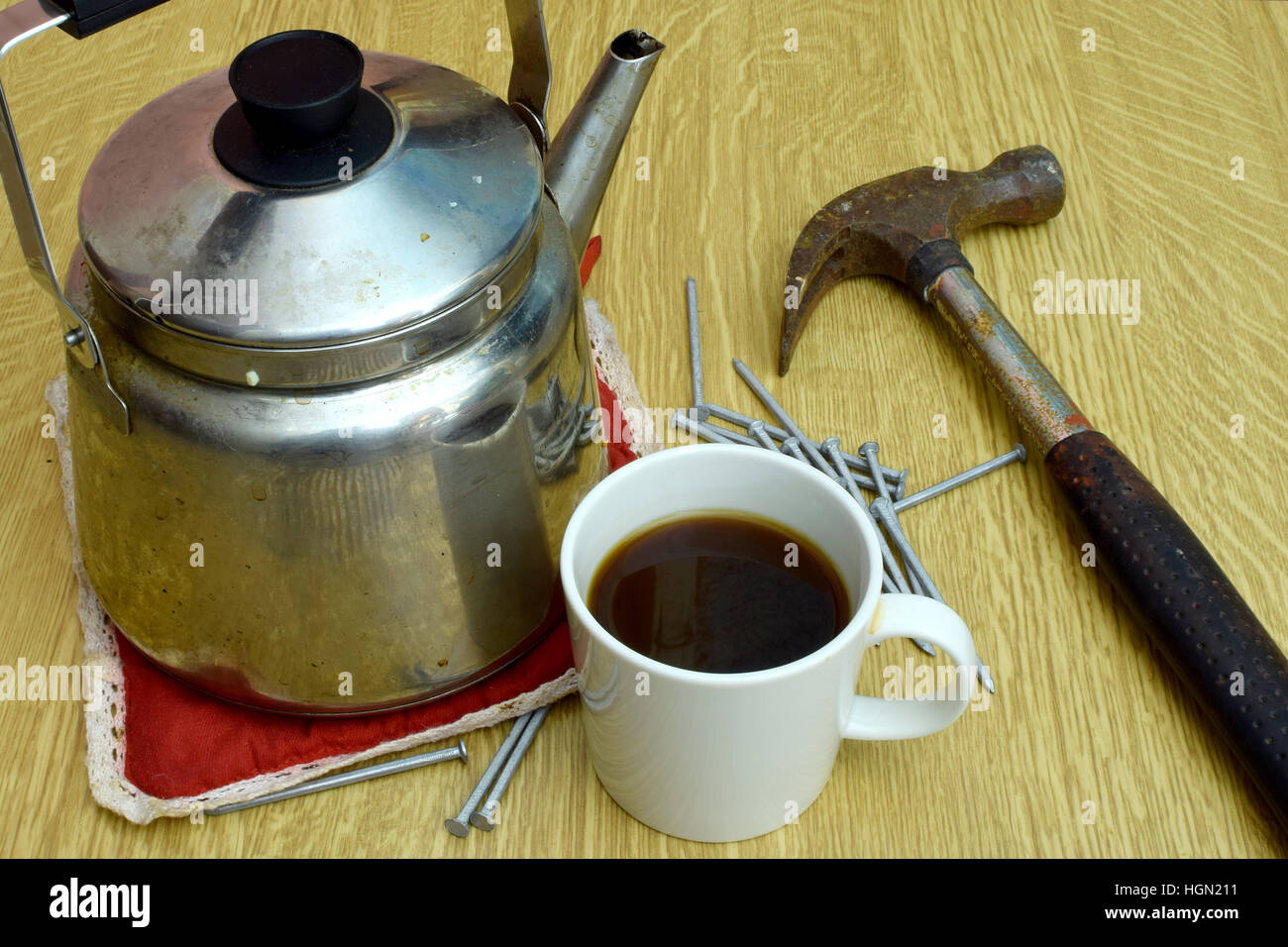 Kaffee-Wasserkocher, Tasse, alte Hammer und Nägel auf dem Tisch. Stockfoto