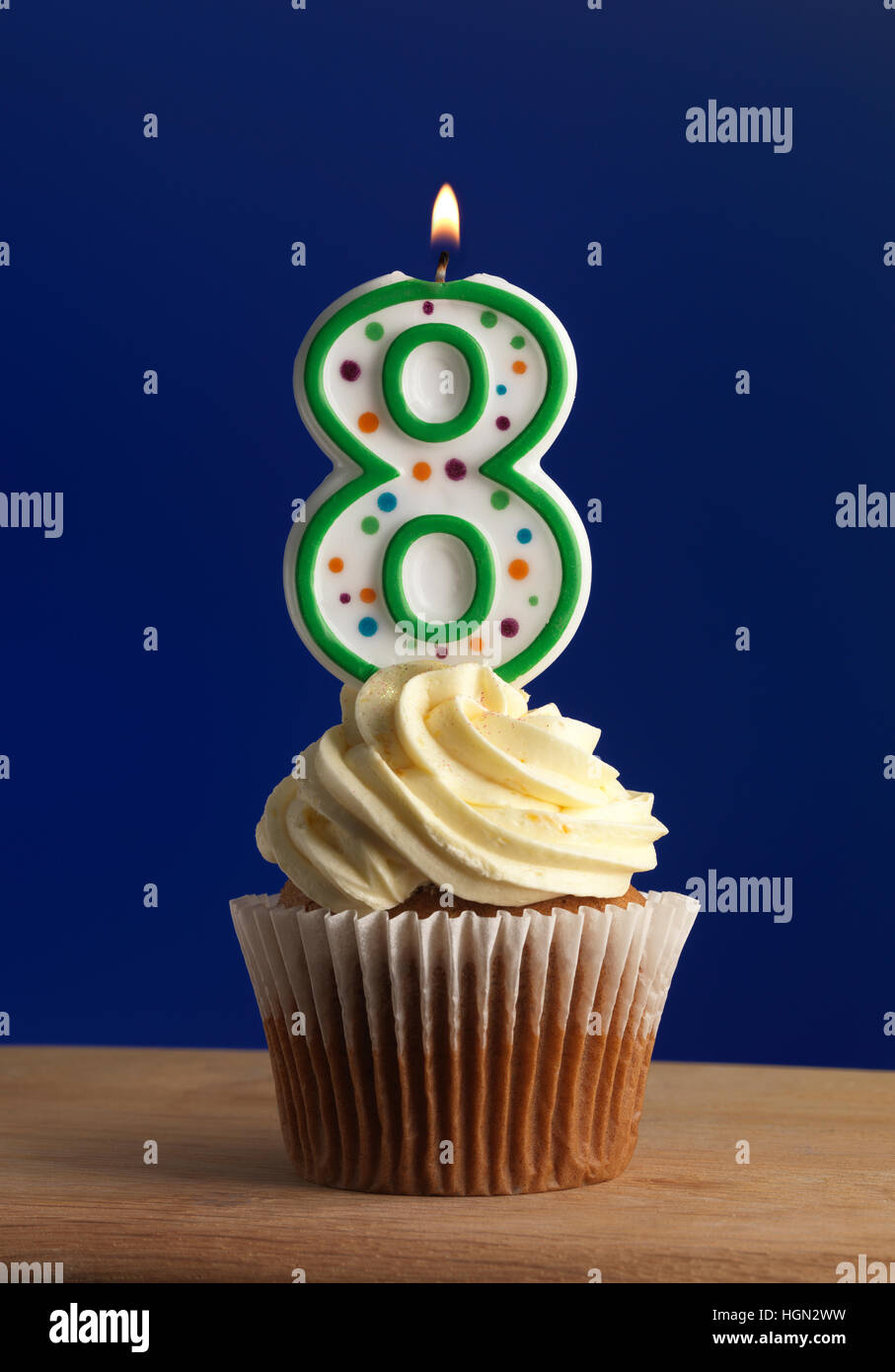 Cupcake mit Zuckerguss und Kerze mit Nummer acht und blauem Hintergrund Stockfoto