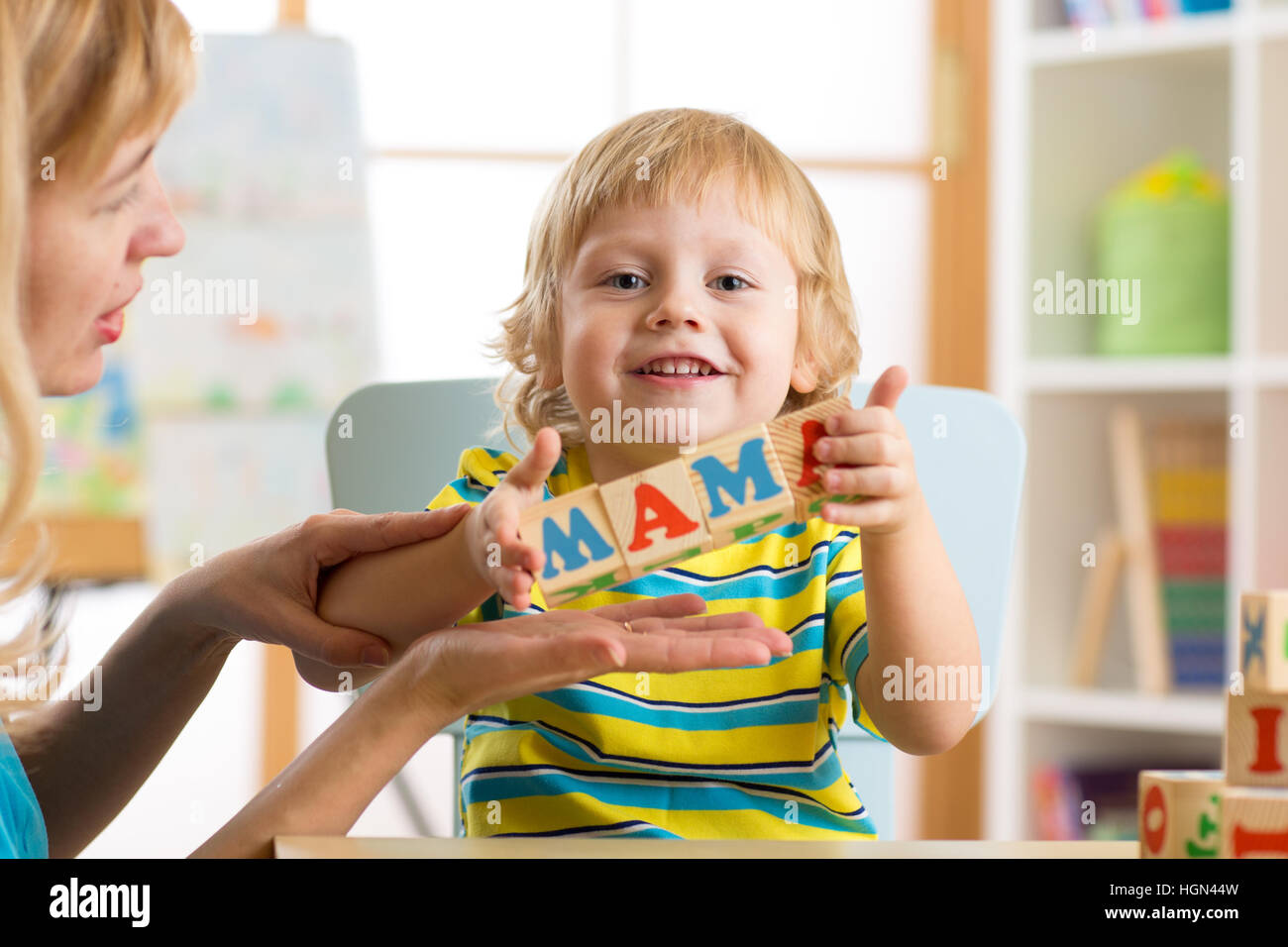 Kid Boy und Mutter bauen das Wort Mama spielen hölzerne Würfel zu Hause Stockfoto