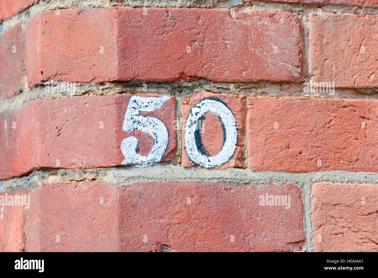 Haus Nummer 50 Zeichen auf roten Backsteinmauer weiß lackiert Stockfoto