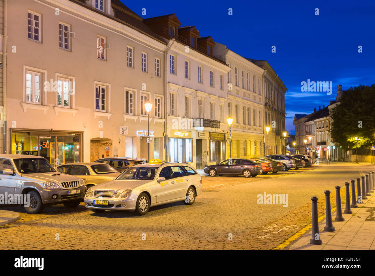Vilnius, Litauen - 8. Juli 2016: Die bewegungslos silbernen Mercedes-Benz Taxi Auto unter parkenden Autos auf dem verlassenen Rotuses Platz In Abend Illumin Stockfoto