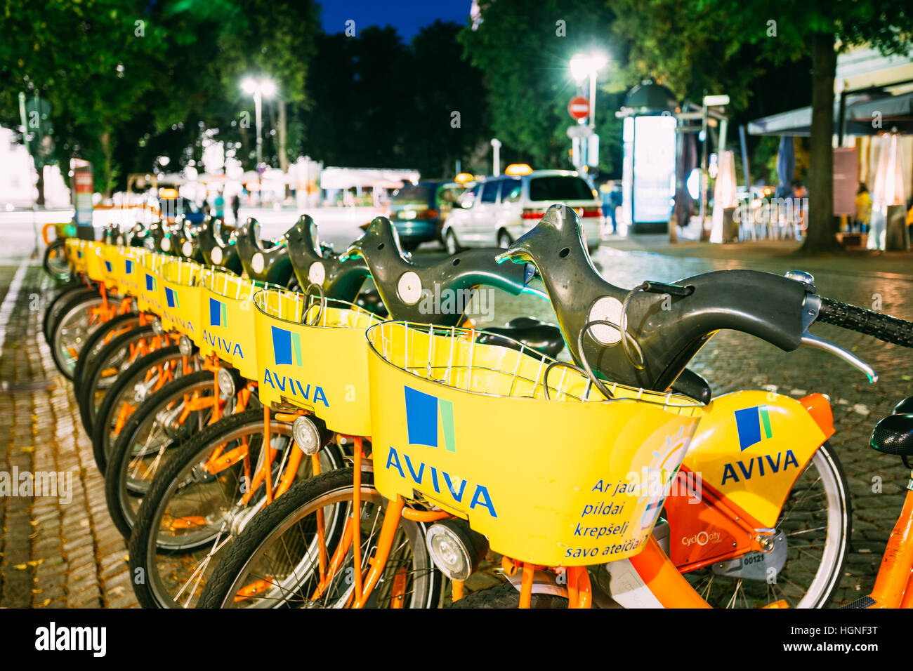 Vilnius, Litauen - 8. Juli 2016: Reihe von Aviva bunte Fahrräder zur Miete an der beleuchteten städtischen Fahrrad-Parken auf nassem Kopfsteinpflaster Pilies Straße, Bevölkerung Stockfoto