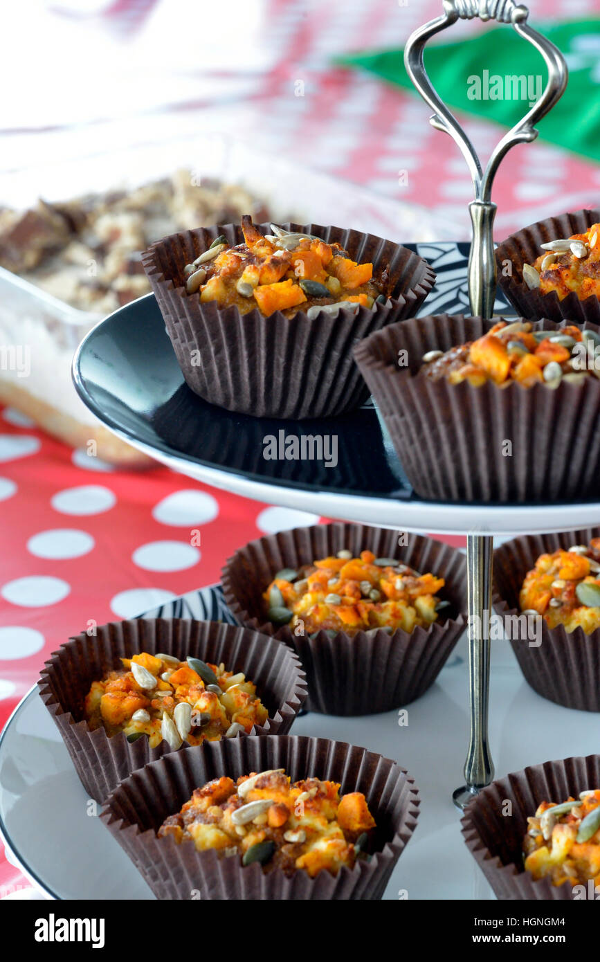 Kürbiskerne und Butternut-Kürbis-Muffins in braunen Cupcakes auf einem rot-weißen Polka Dot Tischtuch. Stockfoto