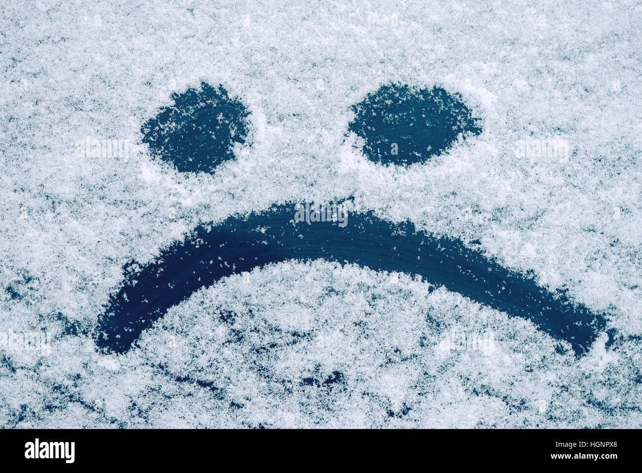 Traurige Smiley Emoticon Gesicht gezeichnet auf schneebedeckten Glas, Winter Saison Traurigkeit Konzept Stockfoto