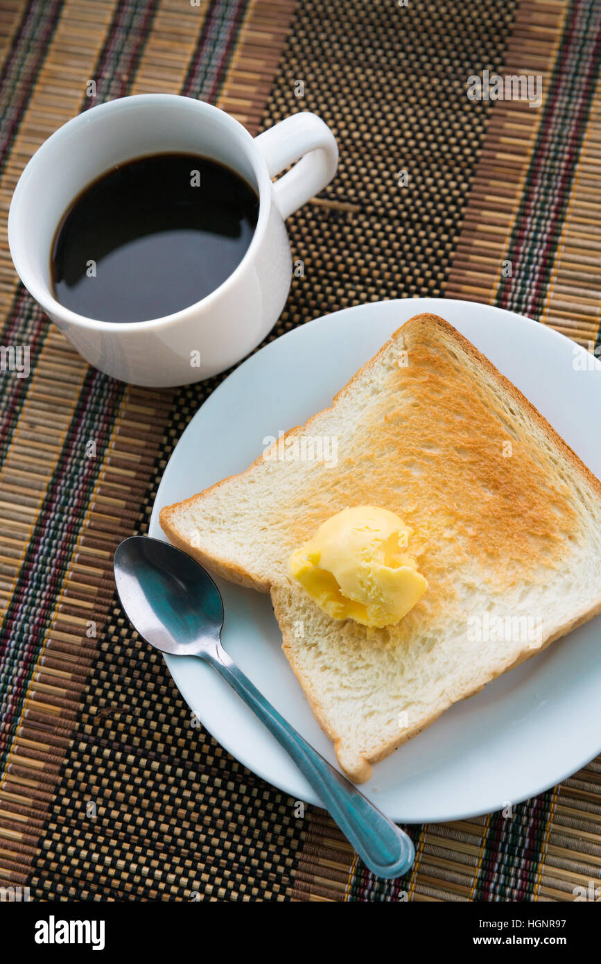 Tisch zum Frühstück mit Kaffee, Toast und Butter auf Bierdeckel serviert Stockfoto