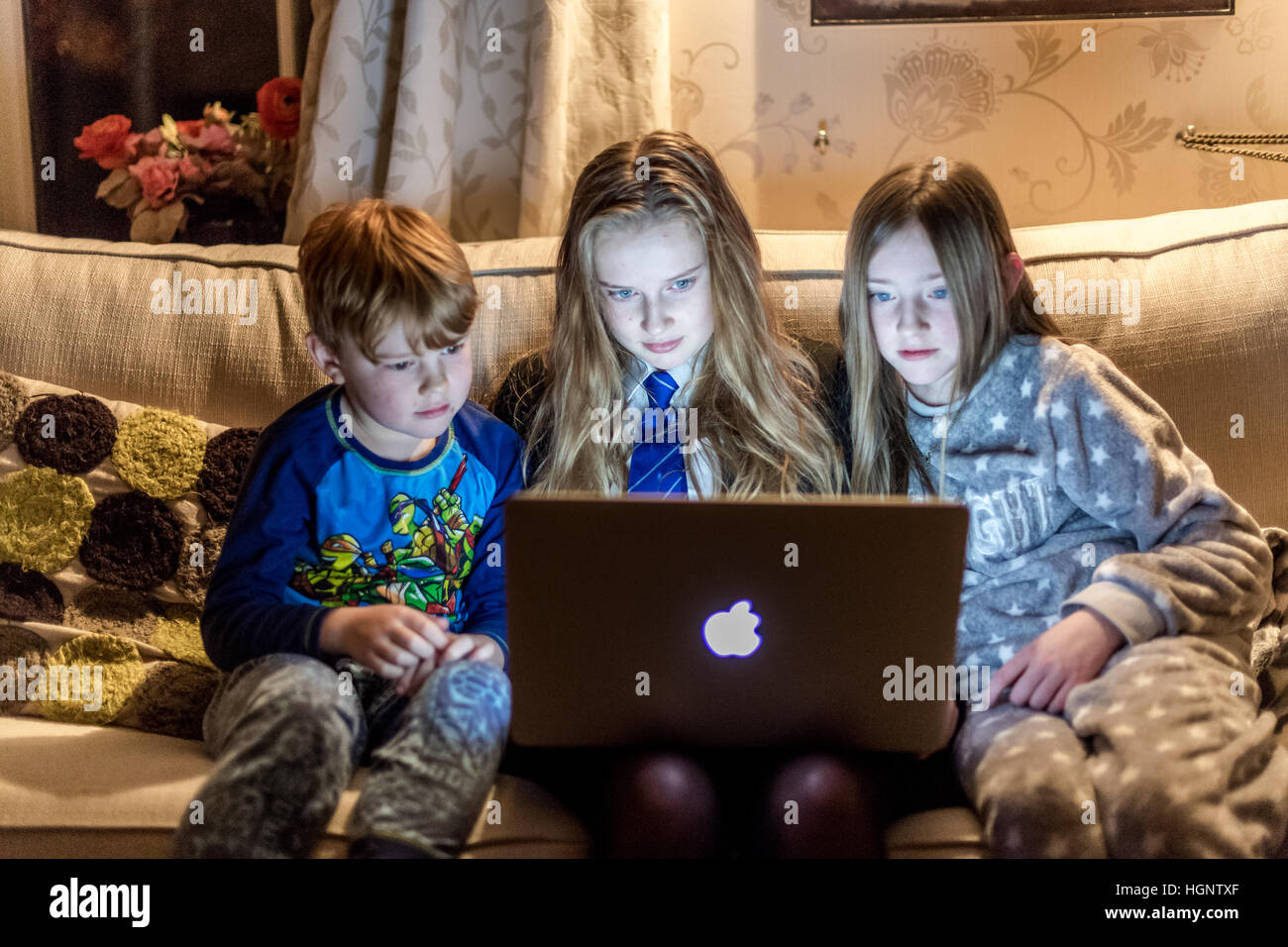 Kinder saßen am Haus auf der Suche an einem Computer lachen bei einer TV-show Stockfoto