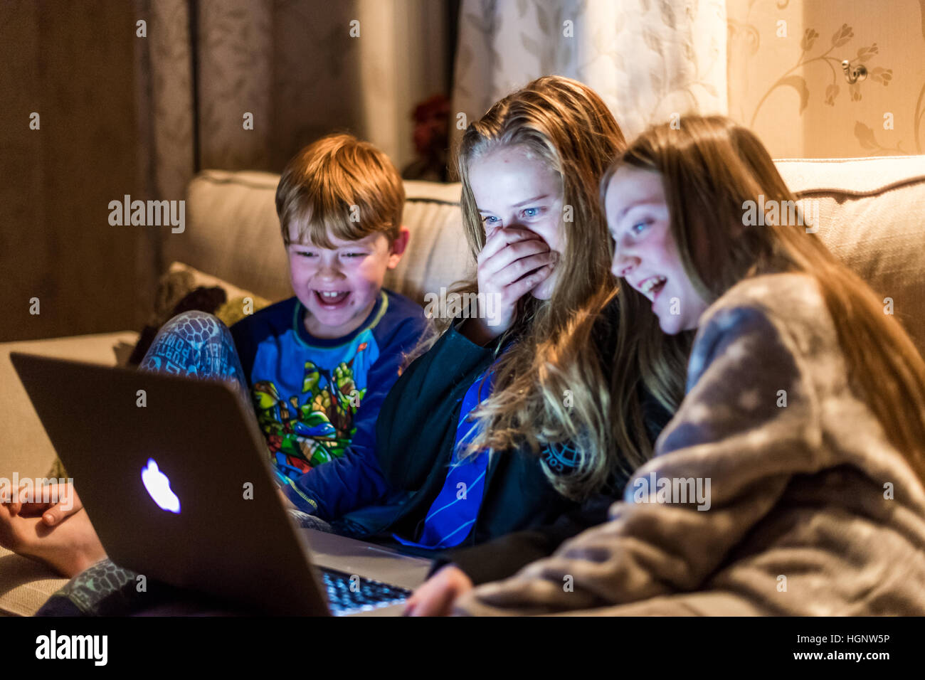 Kinder saßen am Haus auf der Suche an einem Computer lachen bei einer TV-show Stockfoto
