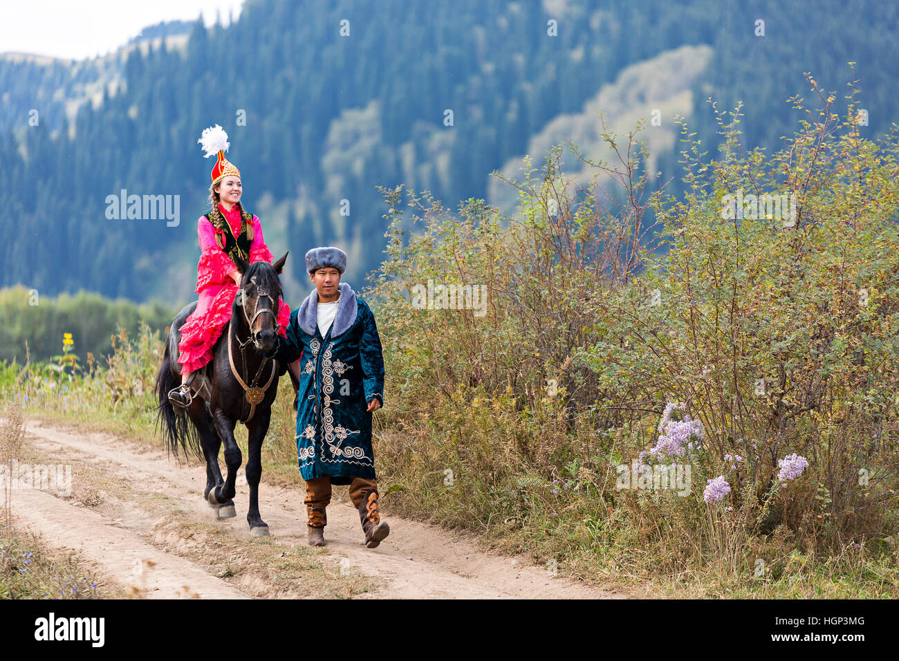 Kasachische Paar in Volkstrachten mit einer einheimischen Frau auf dem Pferd, Kasachstan Stockfoto