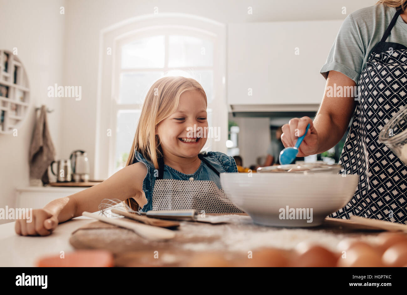Glückliche kleine Mädchen stehend in Küche und ihrer Mutter kochen. Mutter und glückliche Tochter Backen in der Küche. Stockfoto