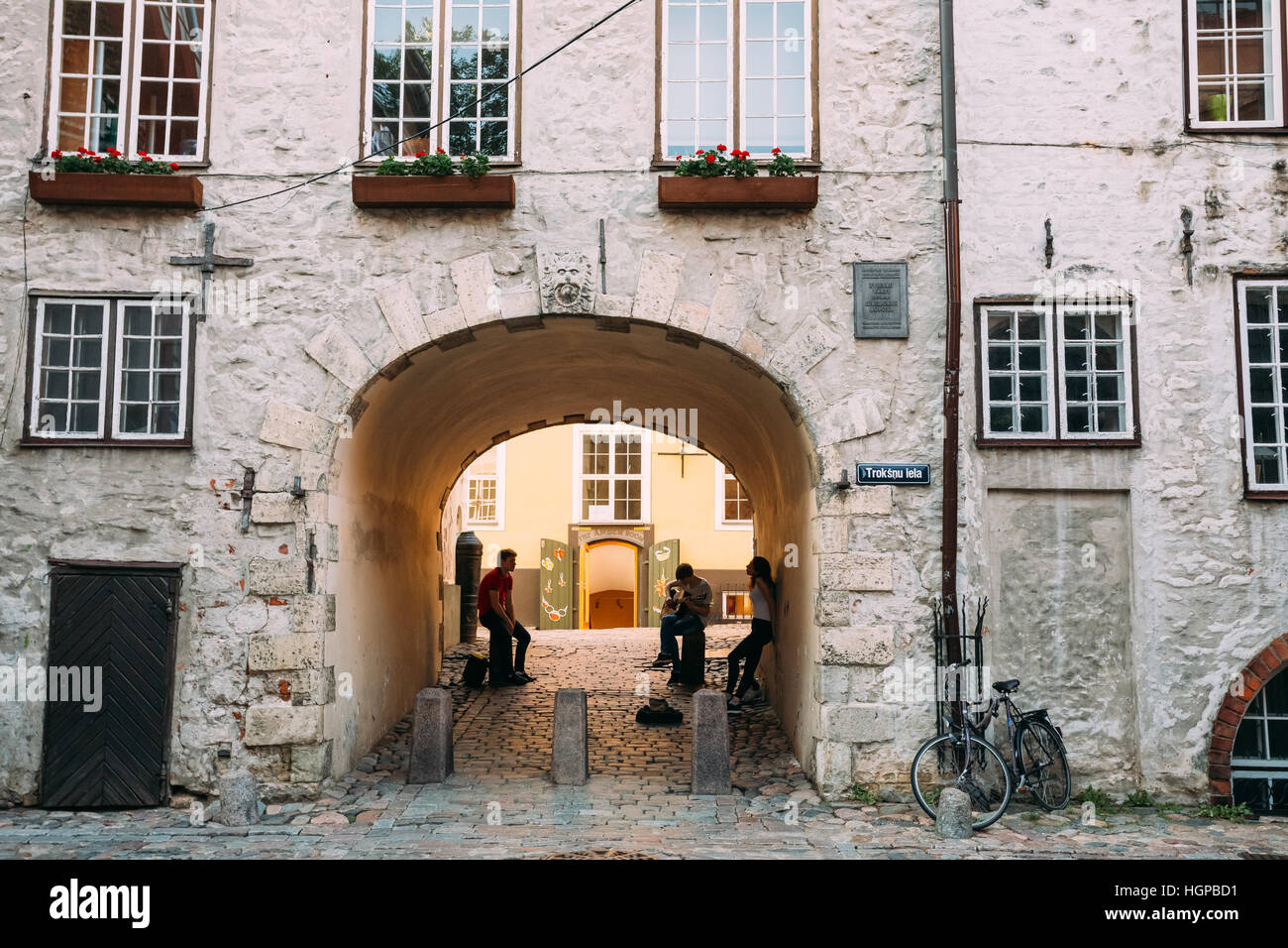 Riga, Lettland - 1. Juli 2016: Drei junge Leute mit Gitarre im Bogen der schwedische Tor im Original Zustand auf Troksnu Straße In der Altstadt. Kulturdenkmal Stockfoto