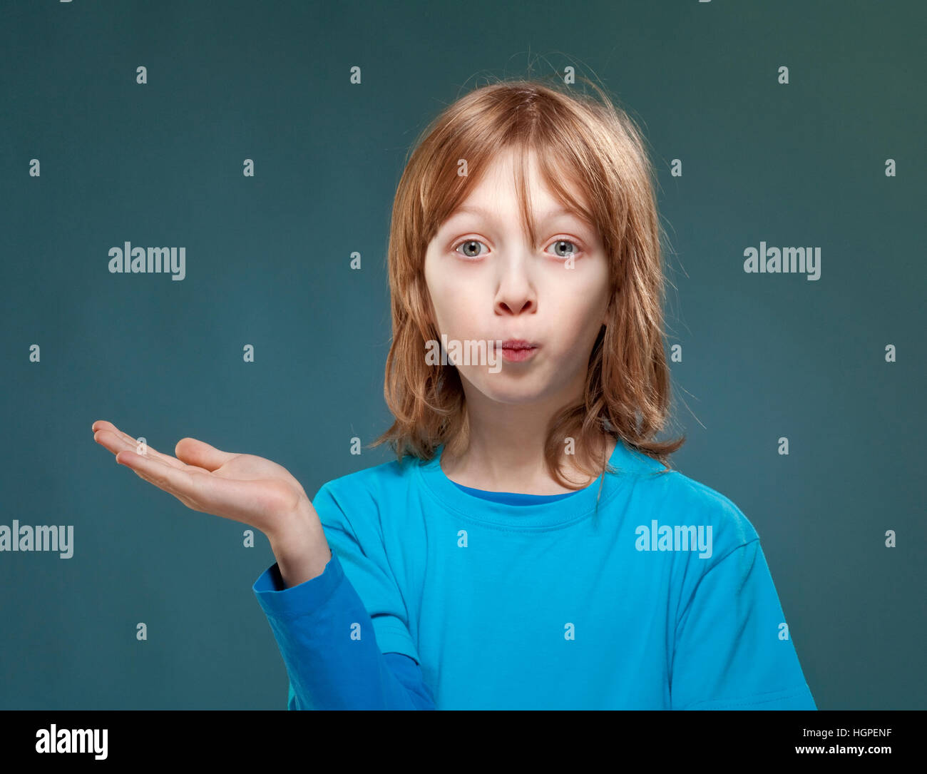 Junge im blauen Top sucht mit seiner Handfläche ausgestreckt. Stockfoto