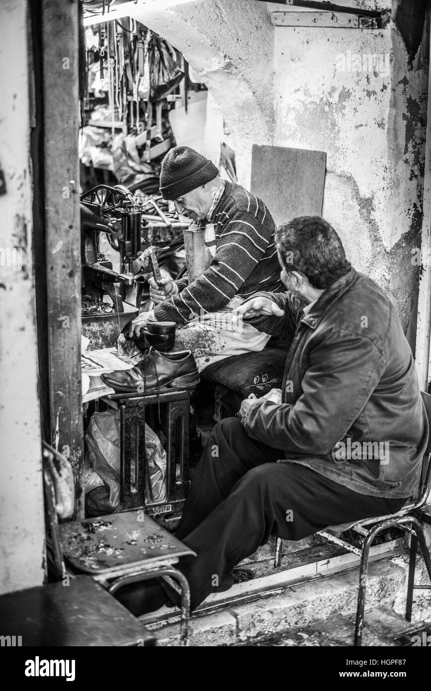 Mann sitzt vor einem Schuhmacher-Werkstatt in der Jerusalemer Altstadt, Israel Stockfoto